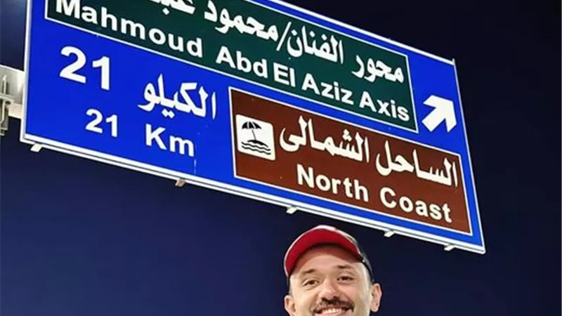  كريم محمود عبدالعزيز يلتقط صورة أسفل لافتة أحد المحاور باسم والده